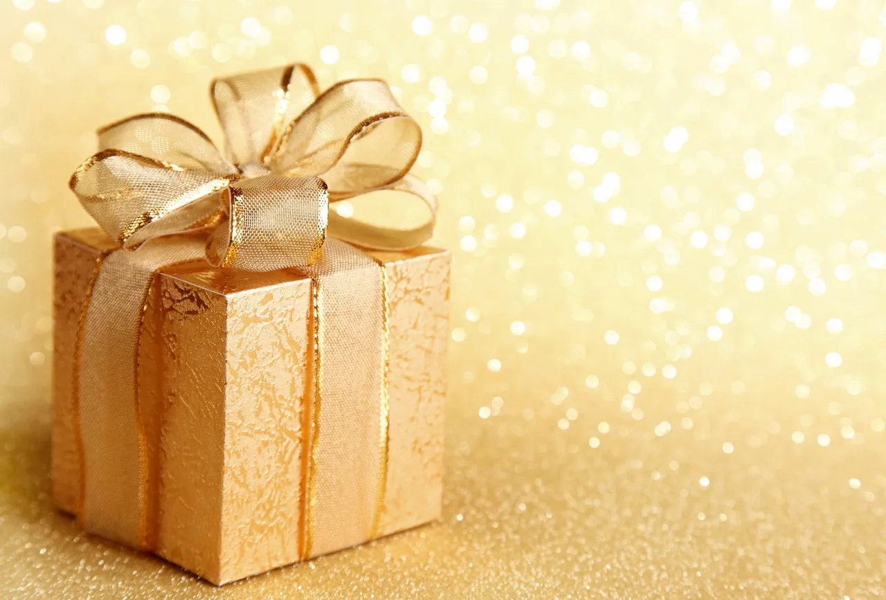 A gold gift box with a bow on top of it.