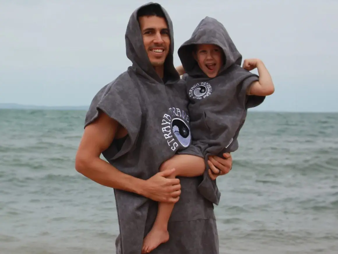 A man and child in the ocean wearing towels