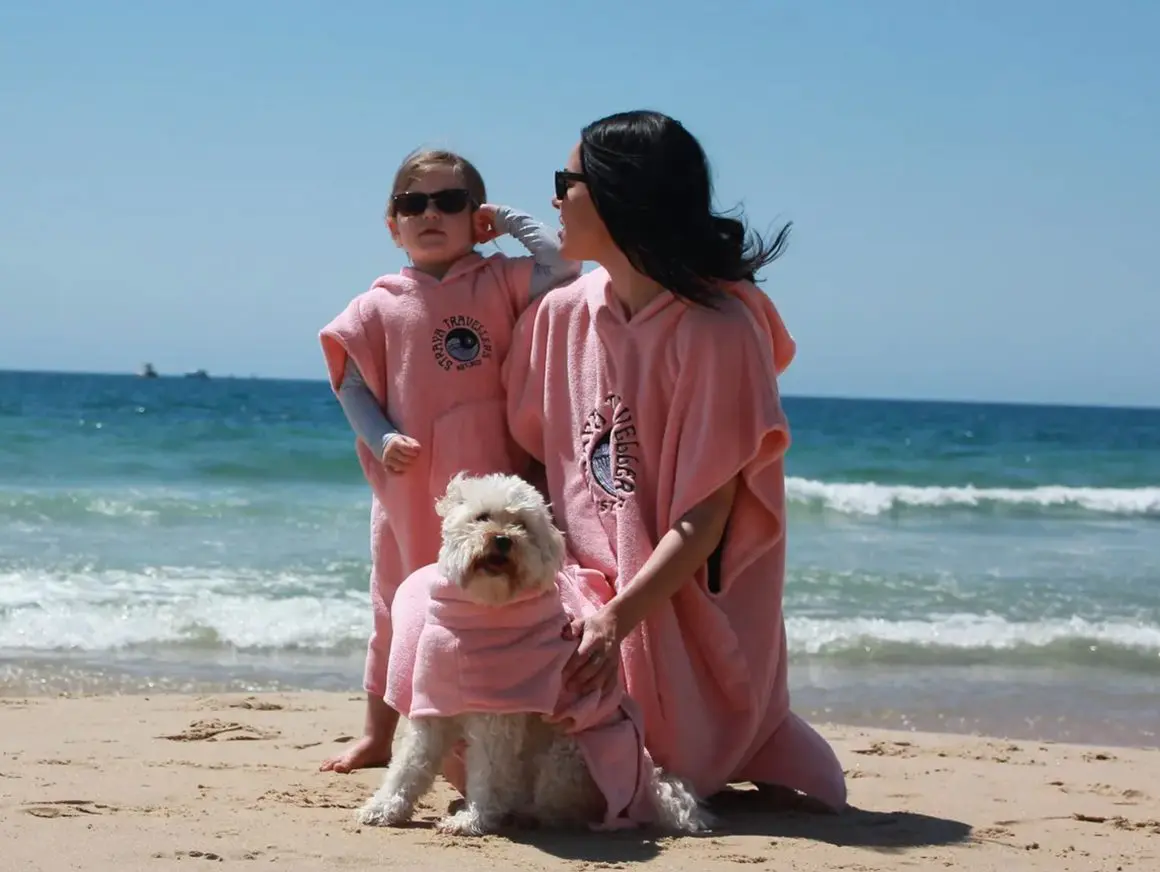 A woman and two children on the beach with their dog.