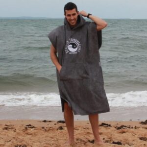 A man standing on the beach with his hands in his pockets.