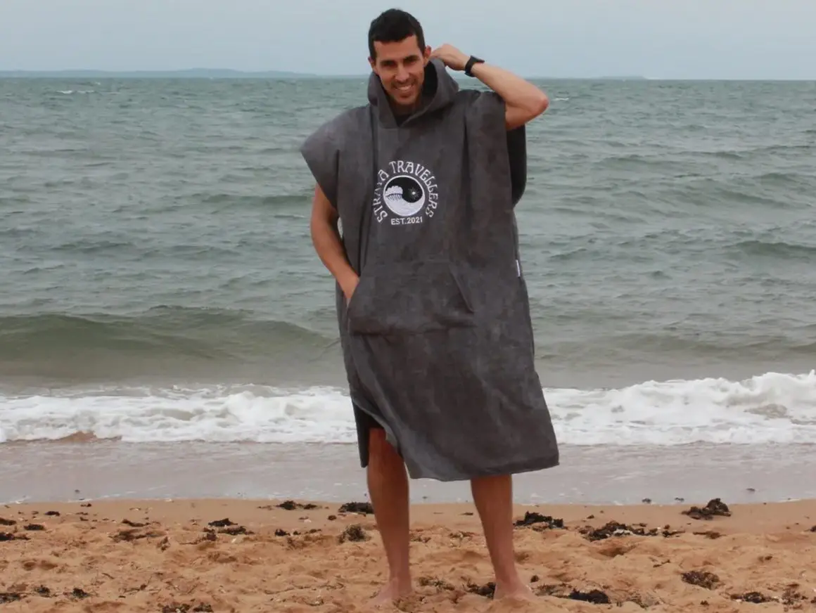 A man standing on the beach with his hands in his pockets.