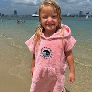 A little girl in pink is standing on the beach