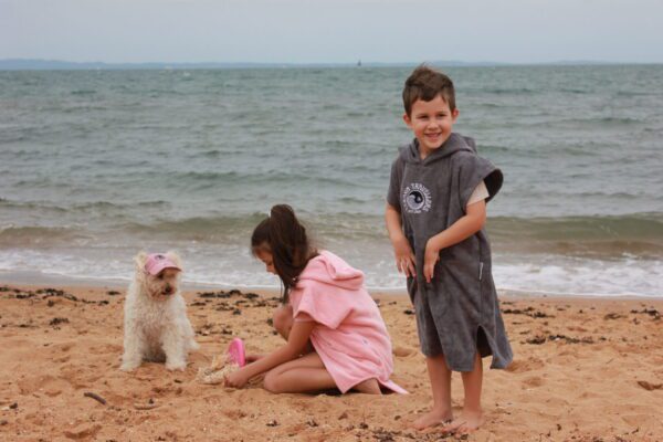 A boy and girl playing with a dog on the beach.