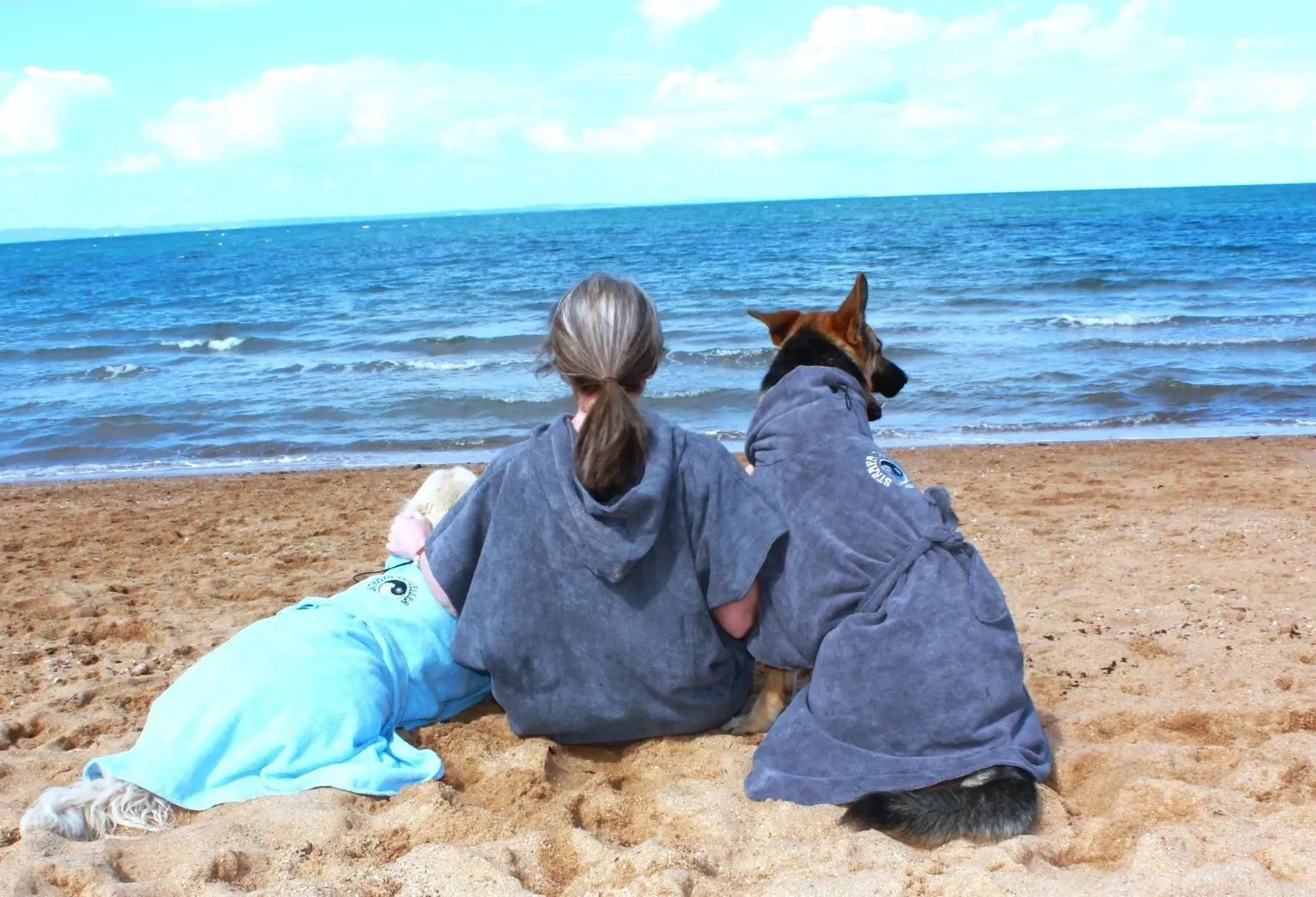 A woman and her dog sitting on the beach