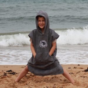 A child sitting on the beach wearing a towel