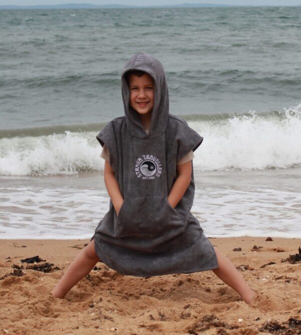 A child sitting on the beach wearing a towel